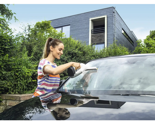 Žena čistí čelné sklo automobilu pomocou okenného vysávača.