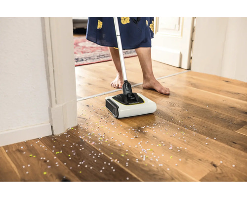 Akumulátorová metla v prevádzke na drevenej podlahe s konfetami