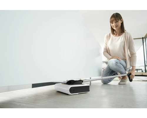 Žena používa elektrickú zametaciu kefu na čistenie podlahy