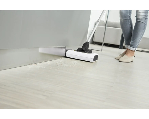 Osoba vysáva podlahu vysávačom