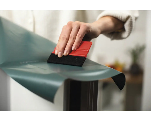 Osoba aplikuje ozdobnú fóliu pomocou stierky