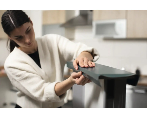 Žena montuje nábytok v kuchyni.