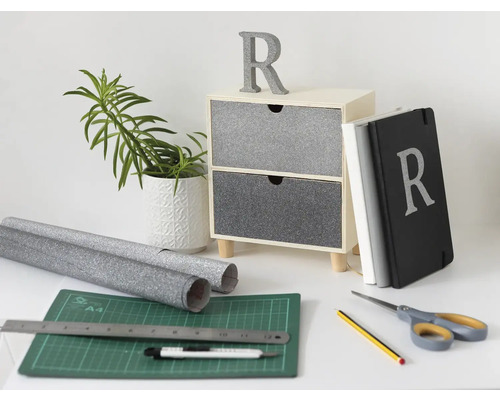 Dekoračná scéna s komodou, rastlinou, zápisníkom, rezacou podložkou, rolkami a nástrojmi