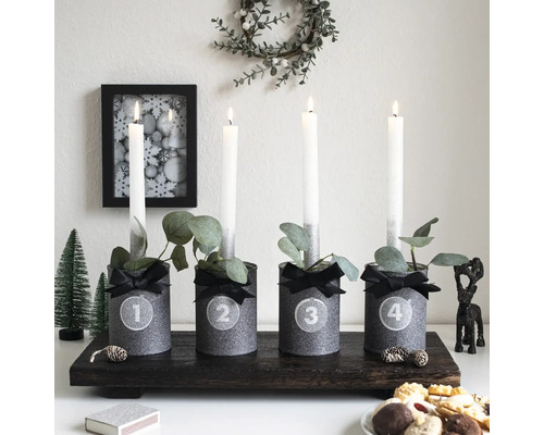 Adventné aranžmán so štyrmi sviečkami a dekoráciami na tmavom drevenom podnose.