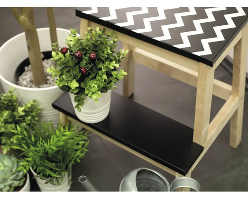 Dekoratívna scéna s malou stoličkou so vzorom cikcak a rôznymi izbovými rastlinami.