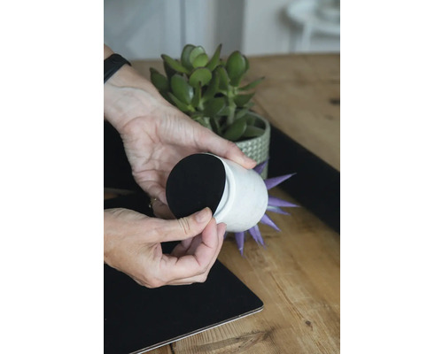 Ozdobný kvetináč s plstenými klzákmi umiestnený na povrchu stola.