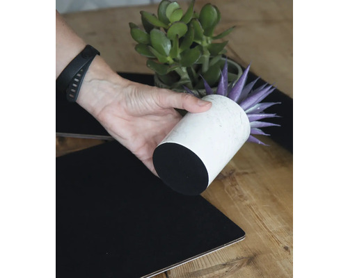 Dekoratívne aranžmán s umelou rastlinou v bielom kvetináči a čiernym obrusom.