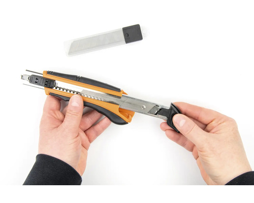 Ruky držia rezací nôž s náhradnými čepeľami