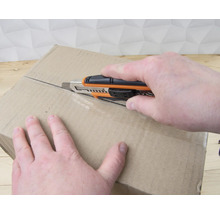 Osoba otvára kartónovú krabicu pomocou odlamovacieho noža.