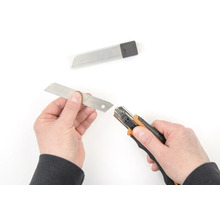 Ruky vymieňajú čepeľ na rezacom noži