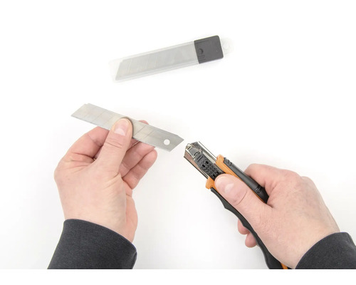 Ruky vymieňajú čepeľ na rezacom noži