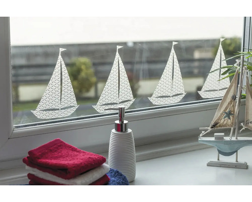 Dekoratívne okno s motívom plachetnice, doplnené uterákmi a dávkovačom mydla