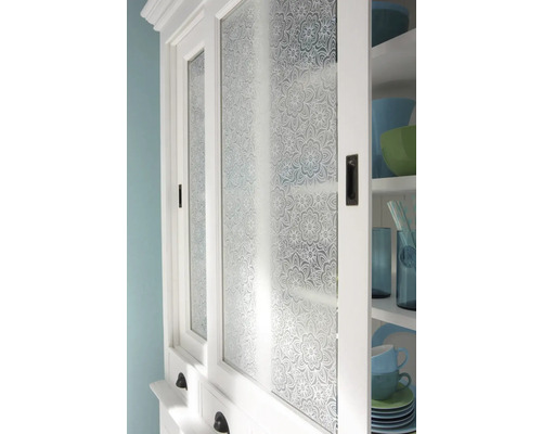 Detail bielej kuchynskej skrinky so sklenenými dvierkami s kvetinovým vzorom.