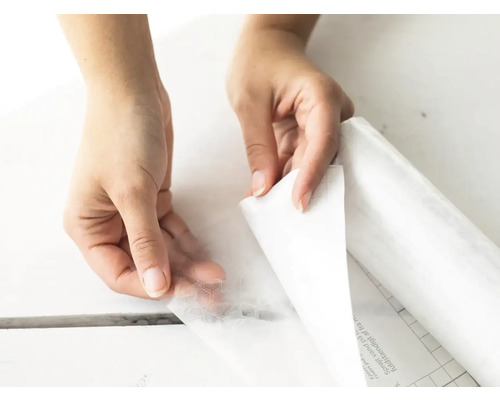 Ruky sťahujú ochrannú fóliu zo samolepiacej dekoratívnej fólie