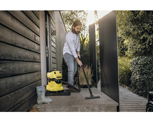 Muž čistí terasu pred domom žltým viacúčelovým vysávačom.