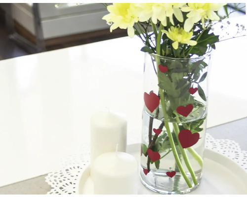 Kvety vo váze so srdcovými motívmi a sviečky ako dekorácia stola