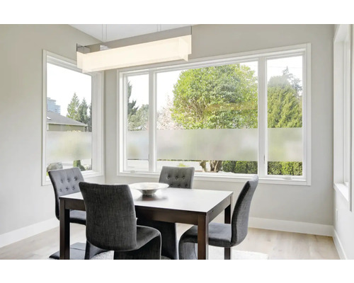 Jedálenský stôl so stoličkami v svetlej miestnosti s oknami a fóliou na ochranu súkromia