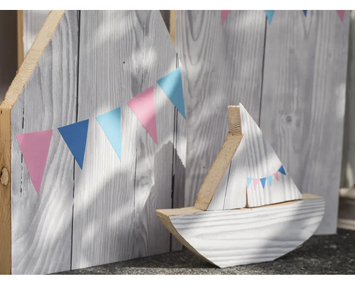 Dekoratívna drevená loď pred drevenou stenou s girlandou z vlajočiek