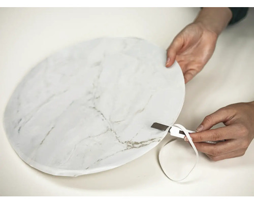 Osoba reže fóliu s mramorovým vzorom nožom.