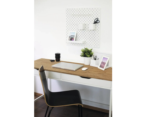 Pracovný priestor so stolom, stoličkou, dierovanou doskou a kancelárskymi potrebami pre usporiadané pracovné prostredie.