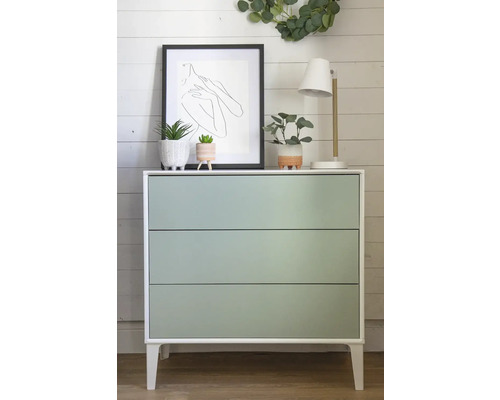 Komoda s tromi zásuvkami, dekoráciami, lampou a obrázkom