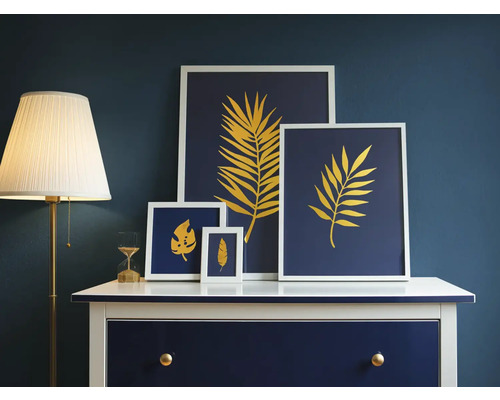 Obrázky dekoratívnych listov v rámoch na komode vedľa stojacej lampy