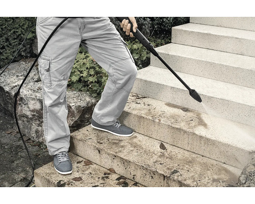 Osoba čistí kamenné schody vysokotlakovým čističom.