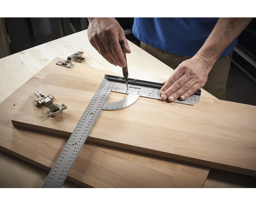 Osoba používa uhlomer a pero na vytváranie značiek na drevenej doske vedľa závesov.