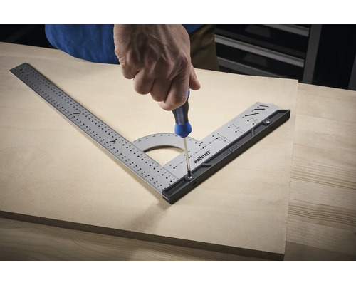 Remeselník skrutkuje multifunkčný uholník na drevenú dosku pomocou skrutkovača