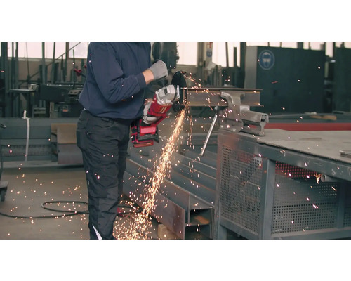 Muž reže uhlovou brúskou kus kovu.