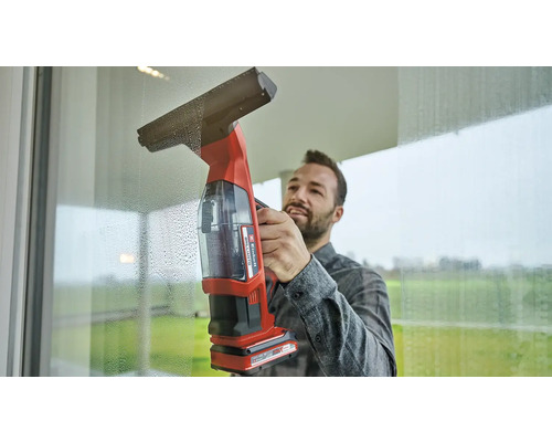 Muž čistí okná pomocou akumulátorovej stierky na okná