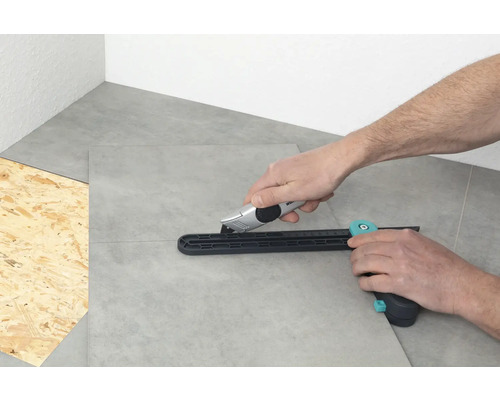 Osoba reže dlaždice rezačkou dlaždíc a rezacím nožom