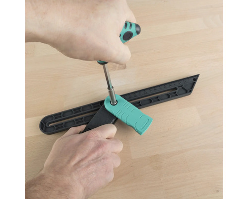 Osoba nastavuje uhlový prípravok skrutkovačom na drevenej podlahe.