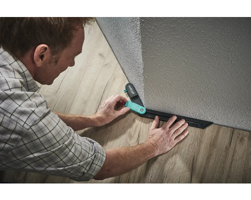 Muž používa rysovaciu šablónu Wolfcraft na kladenie laminátu.