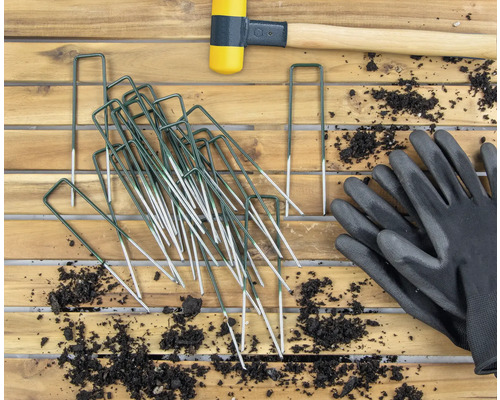 Záhradný záber s kolíkmi, gumovou paličkou a záhradnými rukavicami na drevenom stole