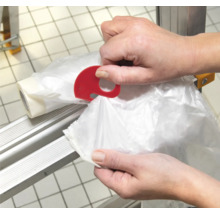 Osoba používa odtrhávač vreciek na odpadky.