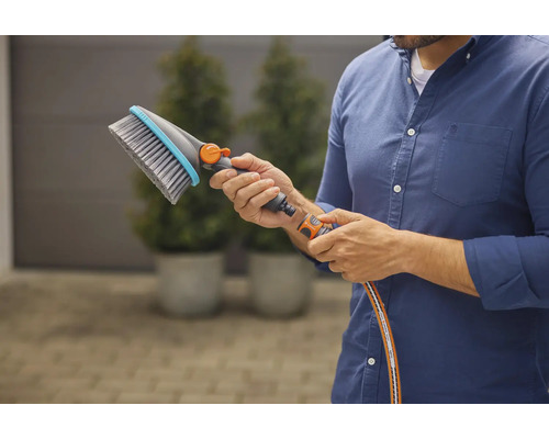 Osoba drží v ruke umývaciu kefu s prípojkou na vodu.