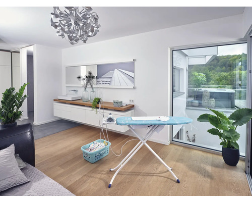 Obývacia izba so žehliacou doskou, žehličkou, košom na bielizeň a izbovými rastlinami