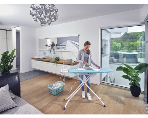 Žena žehlí bielizeň na žehliacej doske vo svetlej miestnosti.