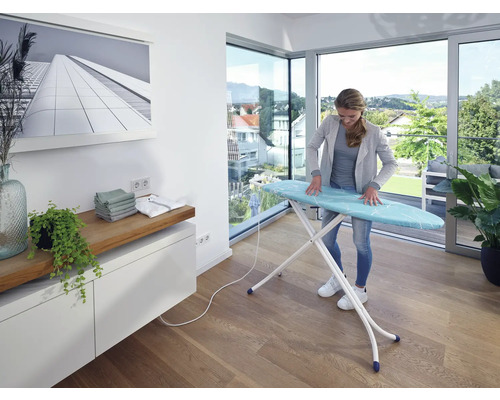 Žena žehlí bielizeň na žehliacej doske v svetlej miestnosti.