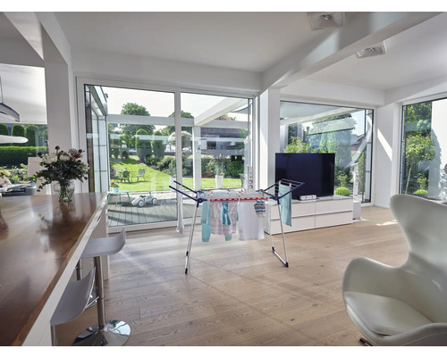 Obývacia izba so sušiakom na bielizeň, drevenou podlahou a výhľadom do záhrady