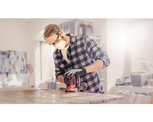 Muž brúsi stolovú dosku excentrickou brúskou