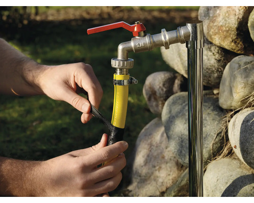 Osoba opravuje záhradnú hadicu izolačnou páskou na vodovodnom kohútiku.