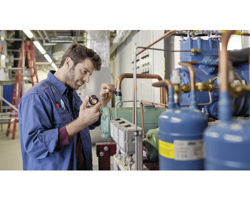 Muž v pracovnom odeve kontroluje chladiacu jednotku v technickej miestnosti.