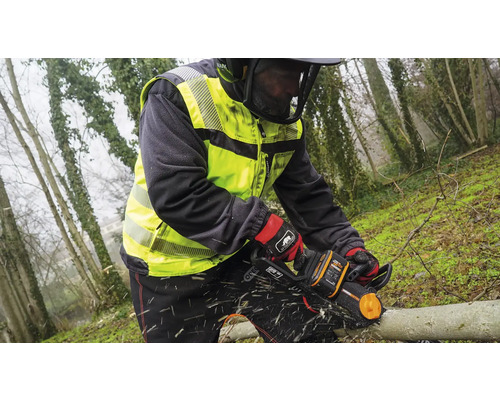 Osoba reže kmeň stromu motorovou pílou, chránená bezpečnostným oblečením.