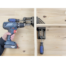 Osoba skrutkuje akumulátorovým skrutkovačom obrobok, ktorý je upevnený pomocou rohového zveráka.