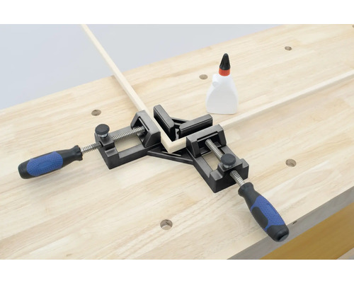 Rohová svorka drží dva kusy dreva v uhle 90 stupňov na pracovnom stole.