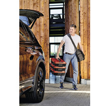 Muž nesie tri kufríky s náradím k autu