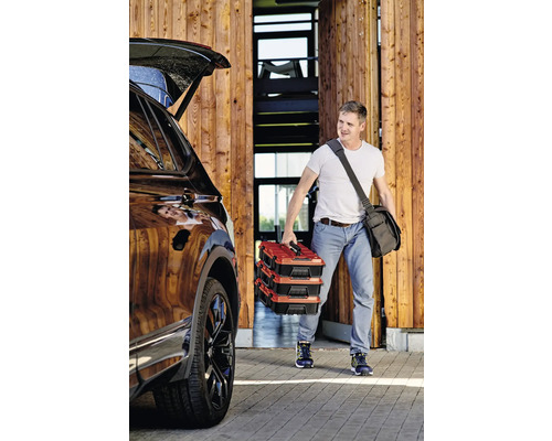 Muž nesie tri kufríky s náradím k autu