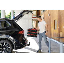 Muž vykladá červené kufríky s náradím z čierneho auta